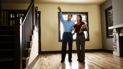Two people standing in an empty room, reviewing the space and pointing upward